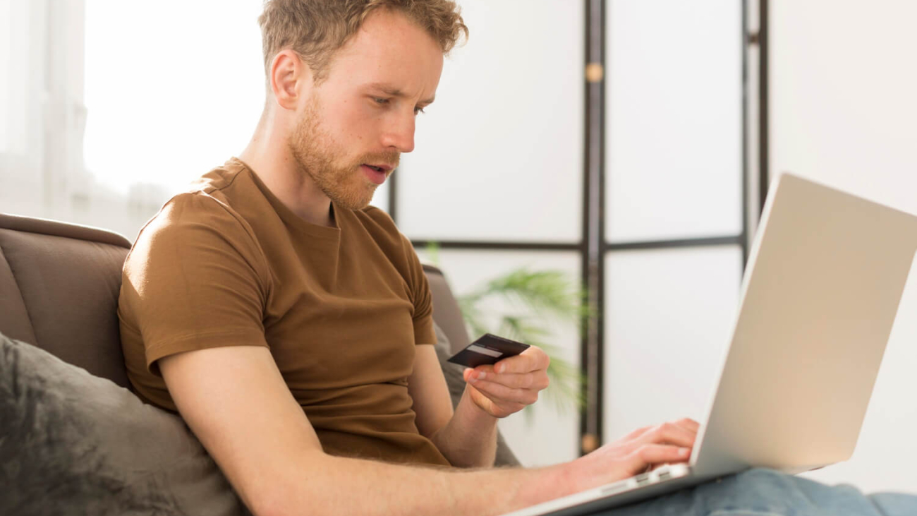 man-holding-credit-card-in-front-of-laptop